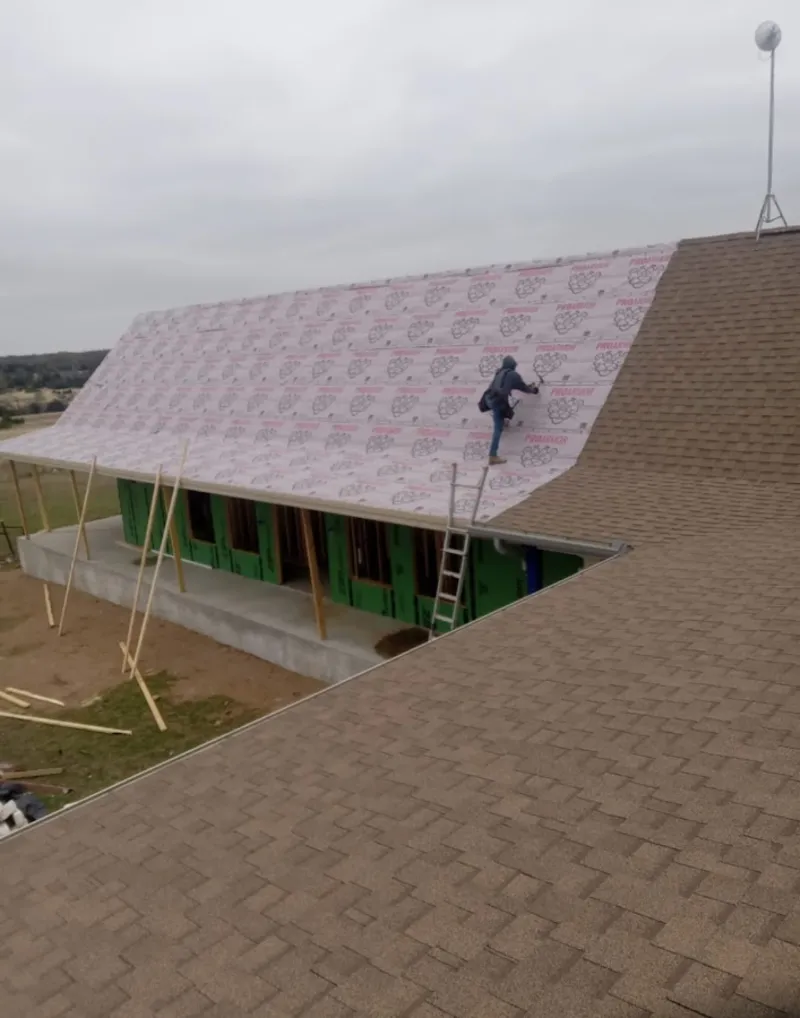 Worker preparing underlayment for a metal roof installation in Maidencreek